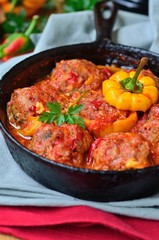 Stuffed bell pepper with minced meat and rice, and meatballs in tomato sauce in a frying pan