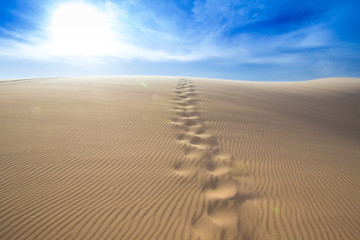 Fototapeta na wymiar Steps of human foot mark on windy white sand dunes, Muine desert, Phan Thiet, Vietnam