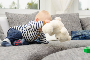 Kleinkind mit Teddy im Wohnzimmer