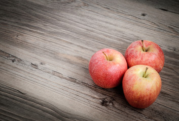 Three fresh apples on table with wooden background