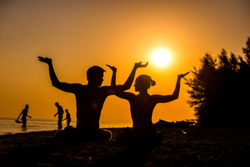 Fototapeta premium An attractive young woman and man doing yoga on the beach, Sea