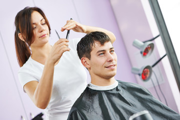 Fototapeta premium Female hairdresser at work making haircut