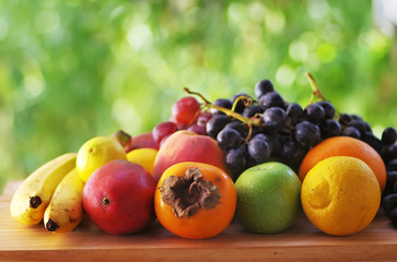 Assortment of ripe fruits on wooden table,green background