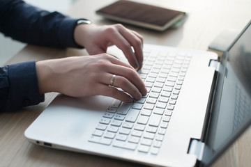 Hands typing on a laptop keyboard. Man works in an office at his workplace
