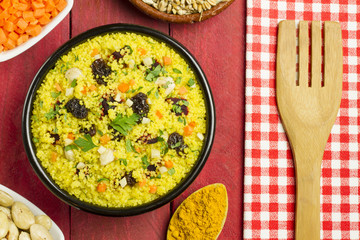 Vegetable couscous in a black bowl with ingredients and spices