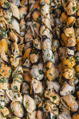 Marinated mussels with herbs and spices on wooden skewers. background