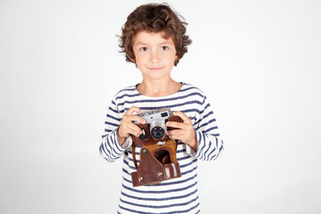  Cheerful smiling child (boy) holding a film camera over white 