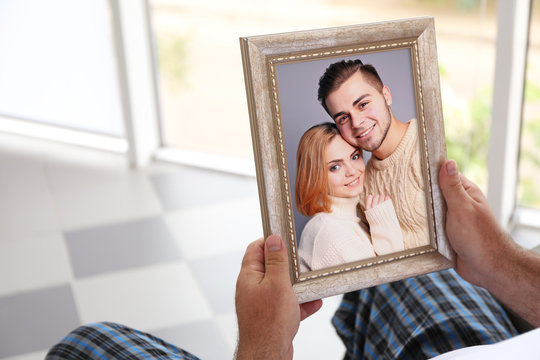 Male Hands Holding Photo Frame With Picture Of Young Couple. Happy Memories Concept.