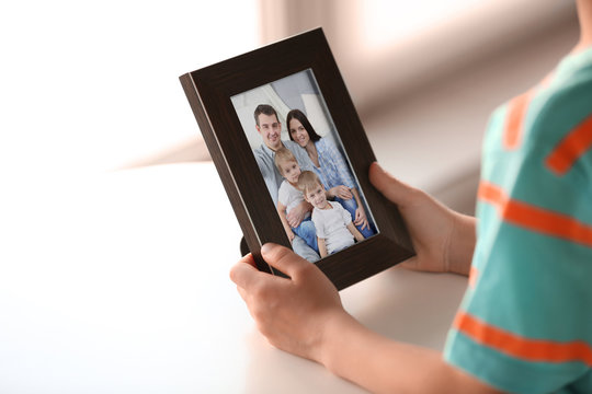 Little boy holding photo frame with picture of family. Happy memories concept.