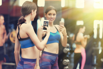 Young sportive woman making selfie into mirror in gym