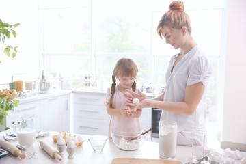 Fototapeta premium Mother and daughter making dough in kitchen