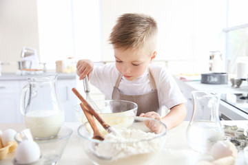 Obraz na płótnie Canvas Little boy in kitchen making dough