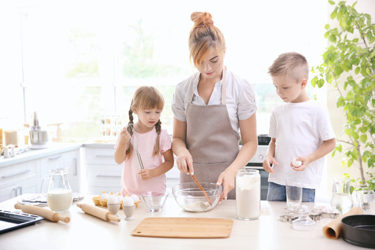 Mother and kids making dough in kitchen