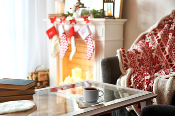 Table with books and cup in living room decorated for Christmas