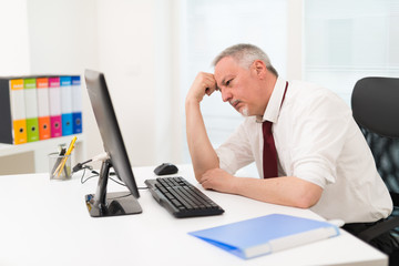 Stressed businessman looking at his computer
