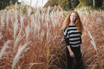 Teenager girl feels natural on the autumn field.