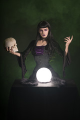 Sexy witch with a human skull in her hand