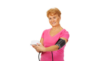 Senior woman measuring blood pressure with automatic manometer