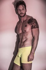 Fototapeta premium Handsome shirtless muscular man, standing, on light background in studio shot