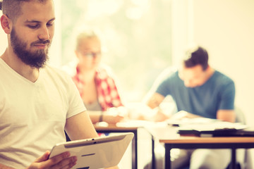 Fototapeta premium Male student with tablet in front of her classmates
