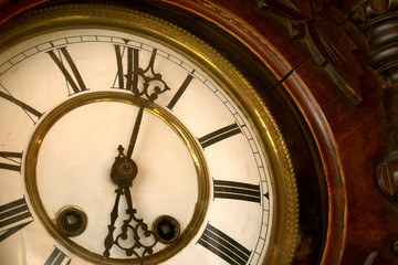 Detail of an old and worn wooden granpa clock with clock-face, hands and frame