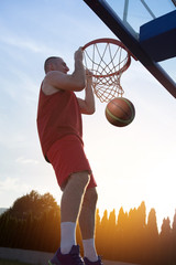 Young man jumping and making a fantastic slam dunk playing stree