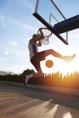 Young man jumping and making a fantastic slam dunk playing stree