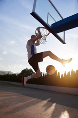 Young man jumping and making a fantastic slam dunk playing stree © FS-Stock
