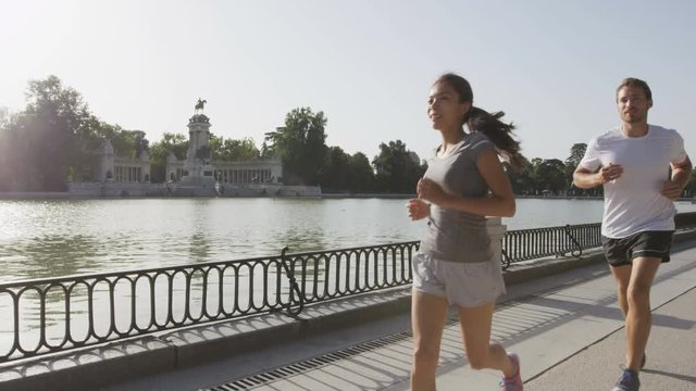 Runners jogging running in Madrid El Retiro city park. Exercising woman and man runner training on jog living healthy lifestyle in Buen Retiro Park, Parque el Retiro in Madrid, Spain, Europe.