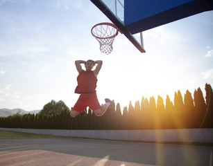 Young man jumping and making a fantastic slam dunk playing stree © FS-Stock