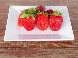 strawberry  on the plate on a wooden table.
