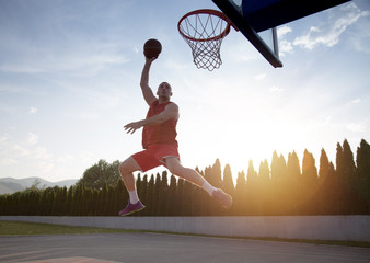 Young man jumping and making a fantastic slam dunk playing stree