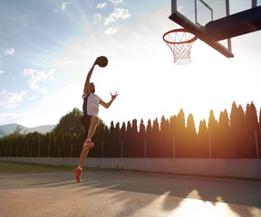 Young man jumping and making a fantastic slam dunk playing stree