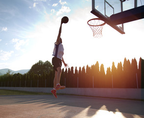Young man jumping and making a fantastic slam dunk playing stree