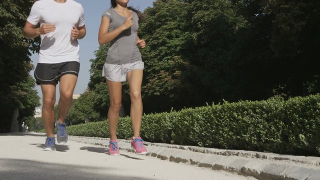 Sport couple running jogging in city park. Runners exercising - woman and man runner training on run living healthy active lifestyle in Retiro Park in Madrid, Spain, Europe. RED EPIC SLOW MOTION.