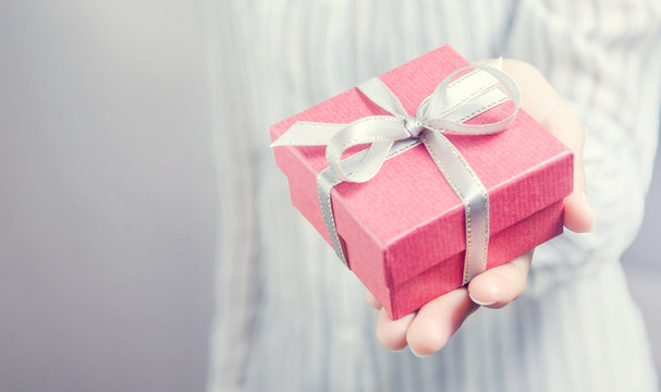 Closeup, Woman hand holding red gift box, female giving gift, New year holidays and greeting season concept, copy space.