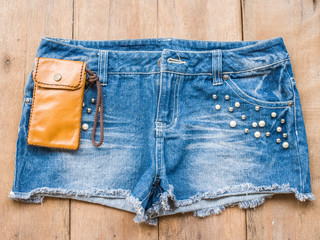 Short jean with leather bag on wood background
