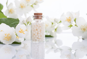 homeopathic pills with spring flowers on white wooden background
