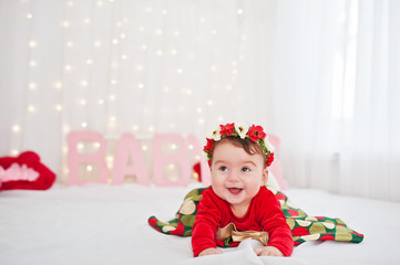 Cute little baby girl with wreath and on red dress posed on the