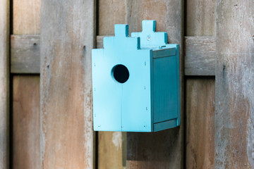 Blue birdhouse on a wooden fence