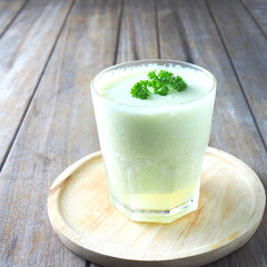 Close up of a glass of melon with yogurt smoothie on a wooden table.
