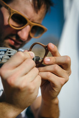 Polishing wooden frame of sunglasses with sander