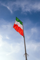 Italian Flag with Pole on Blue Sky with Clouds