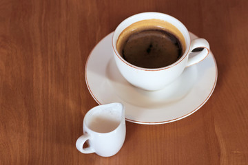 A cup of coffee on the table and a cup of milk