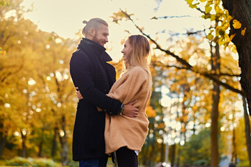 Redhead male hugs cute blonde female in autumn wild nature backg