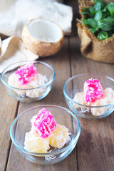 Close up of traditional asian steamed cassava cake with shredded coconut in a bowl on a wooden table.