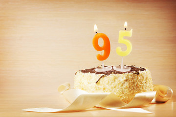 Birthday cake with burning candle as a number ninety five. Focus on the candle