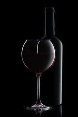 A bottle of champagne and a glass on a black backgroun