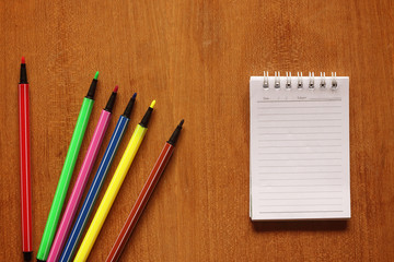 notebook and multicolored pens on wooden table