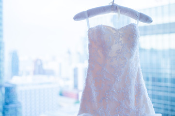 beautiful white luxury wedding dress on hanger on the background of a window. Image in natural light from window